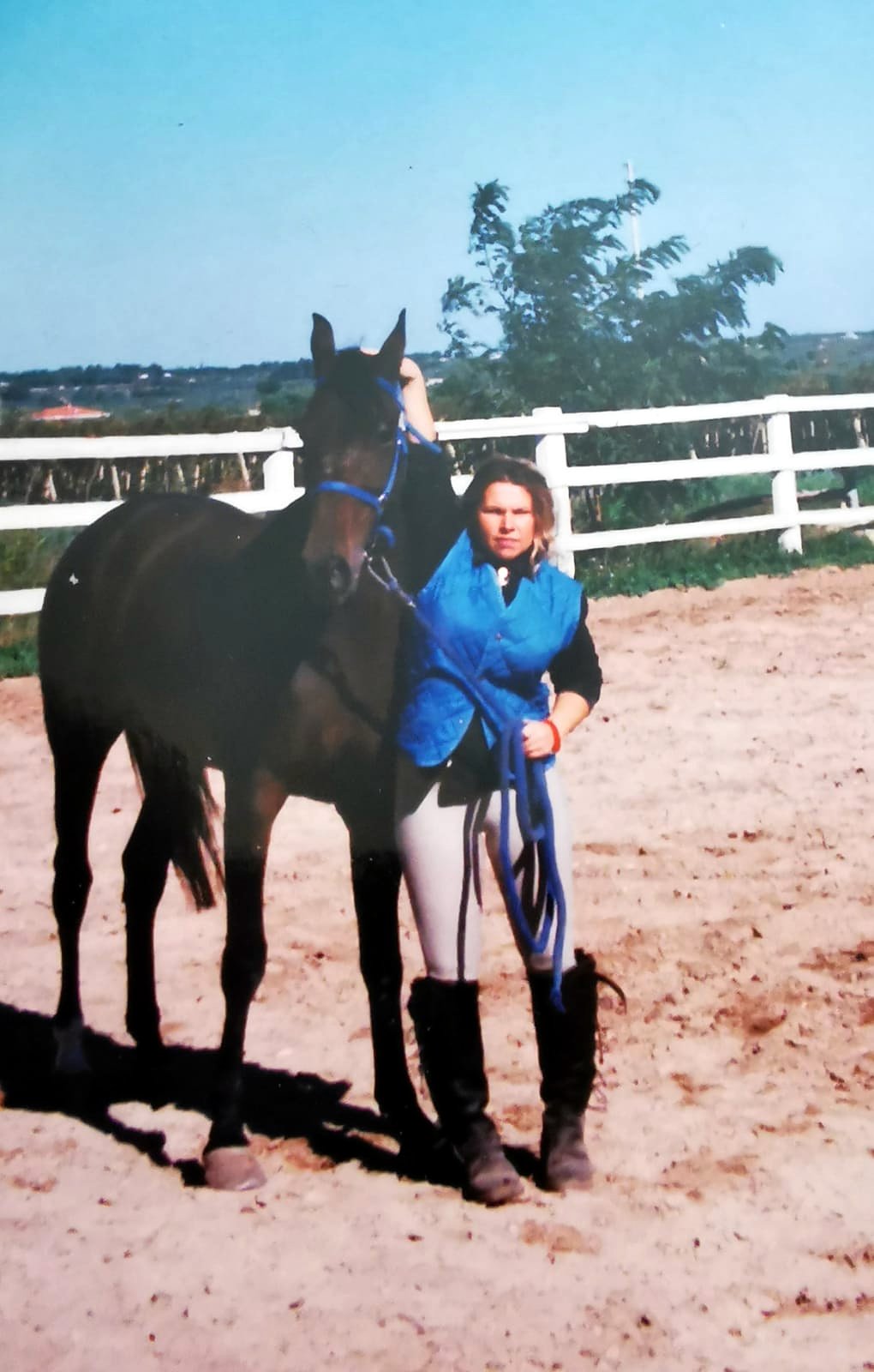 Antonella accanto a un cavallo baio scuro in un campo recintato