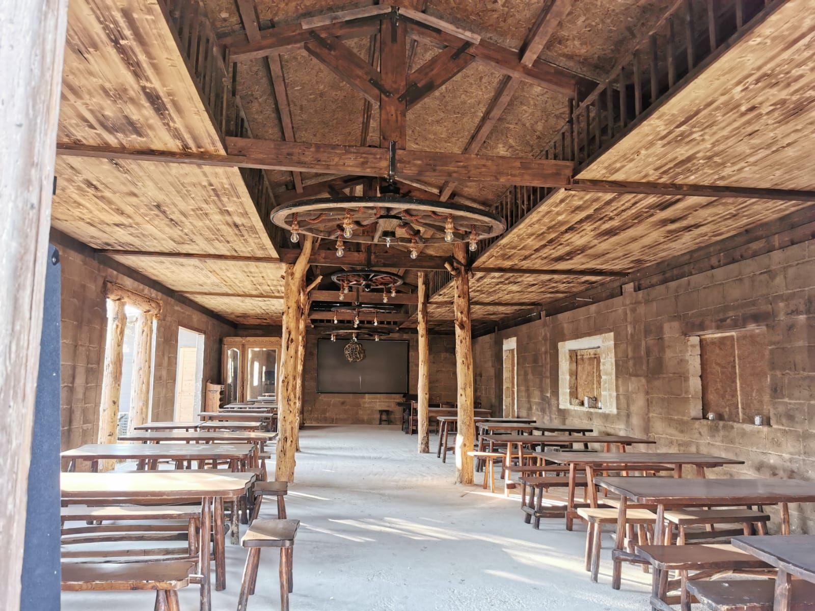 Il saloon: grande sala in legno con tavoli e lampadari a ruota di carro